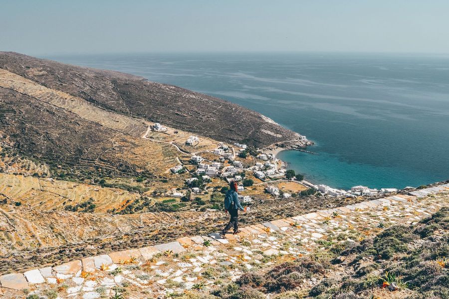 A woman hiking a trail with sea view on Tinos island.