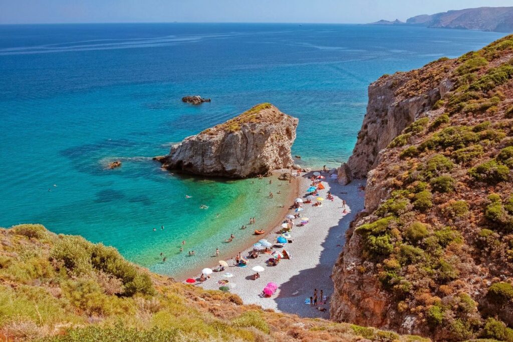 A sandy beach with many people on Kaladi Beach on Kythira Greece.