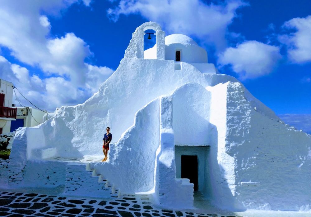 Mykonos best things to do,  woman standing in front of paraportiani church