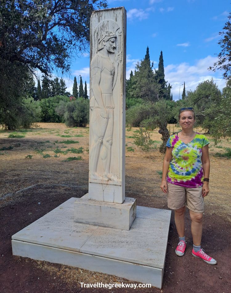 Evgenia standing next to a marble warrior relief at the Marathon Tumulus site in Greece.