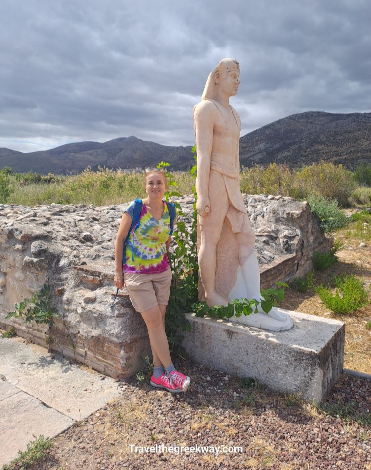 Evgenia leaning on replica statue of an Egyptian pharaoh at the Sanctuary of Egyptian Gods, best things to do in Marathon Greece.