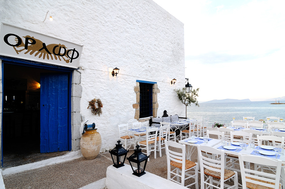 A traditional travern beside the sea with tables and chairs in Old Port in Spetses Greece.