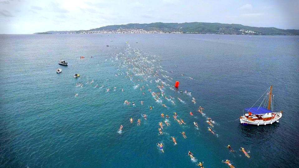 Some swimmers and four boats in Triathlon Race. 