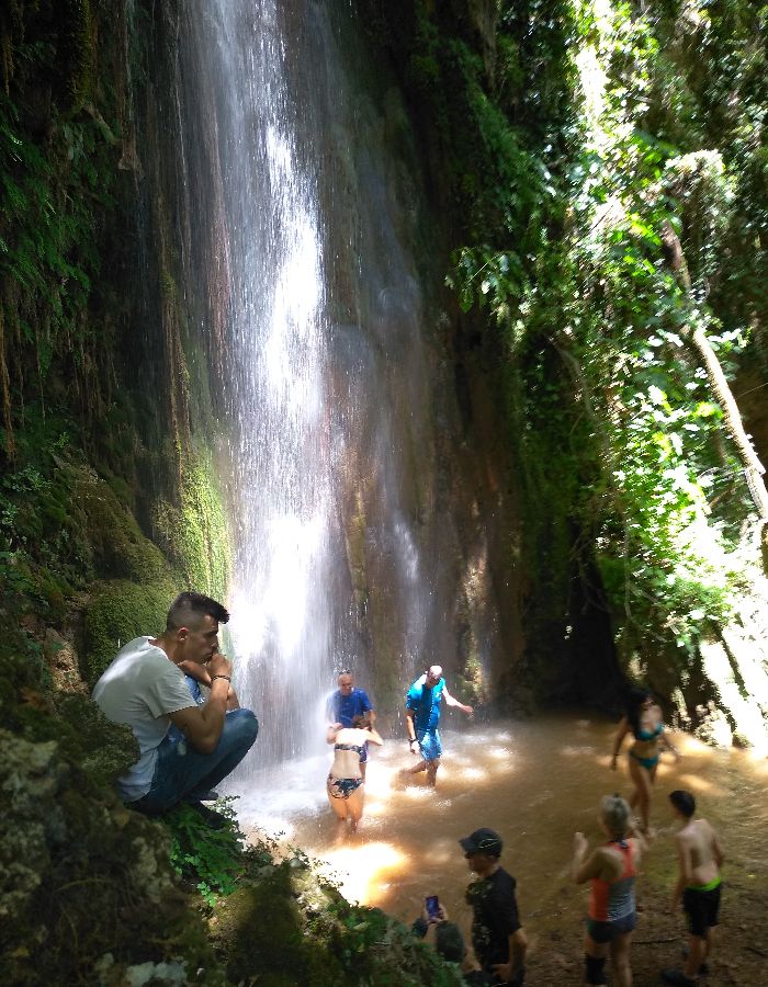 Water fall and some people in it with a lot of green in Nemouta Water falls in Ancient Olympia Greece.