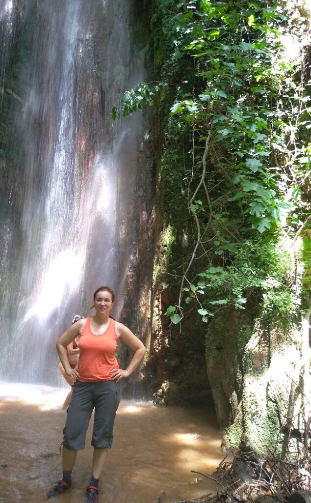 Evgenia beside the water fall in Nemouta Water falls in Ancient Olympia Greece.