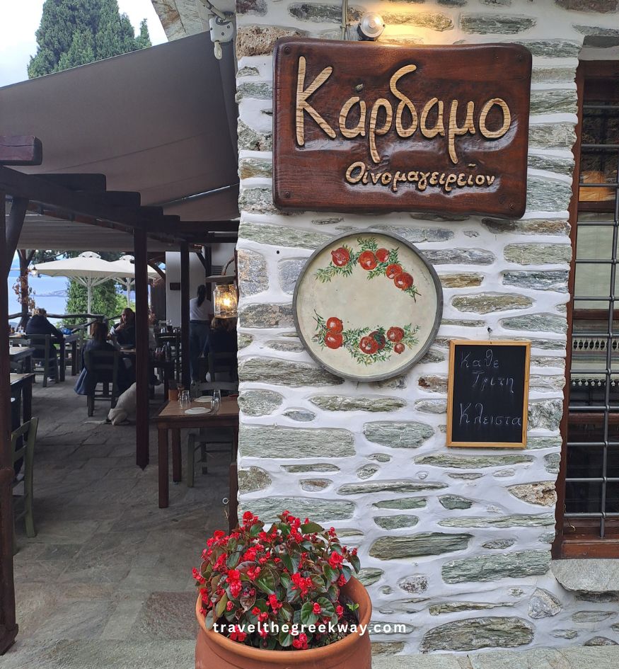 Entrance of Kardamo tavern in Makrinitsa with outdoor seating and flower pot.
