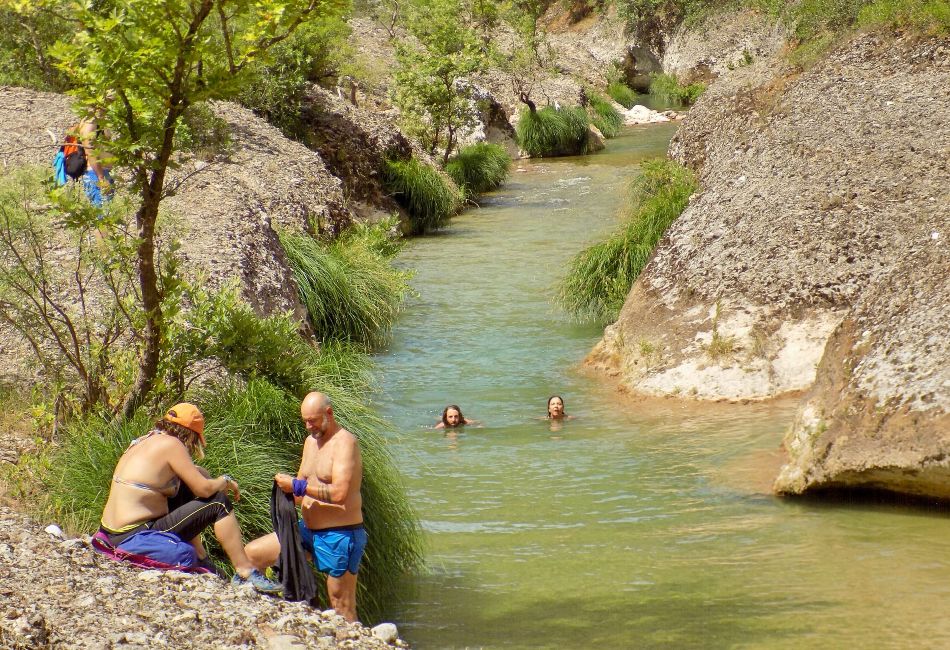 Two people in the Erymanthus River and three more beside in Nemouta Water Falls in Ancient Olympia Greece.