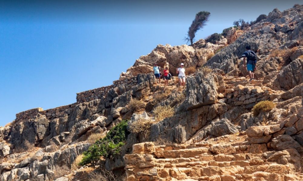 A rocky hill with four people in a sunny day in Chania Crete Greece.