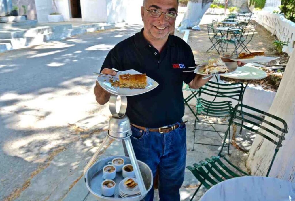 Mr Meletis the owner of kafeneio holding traditional sweats and Greek coffees in Poros Island Greece.