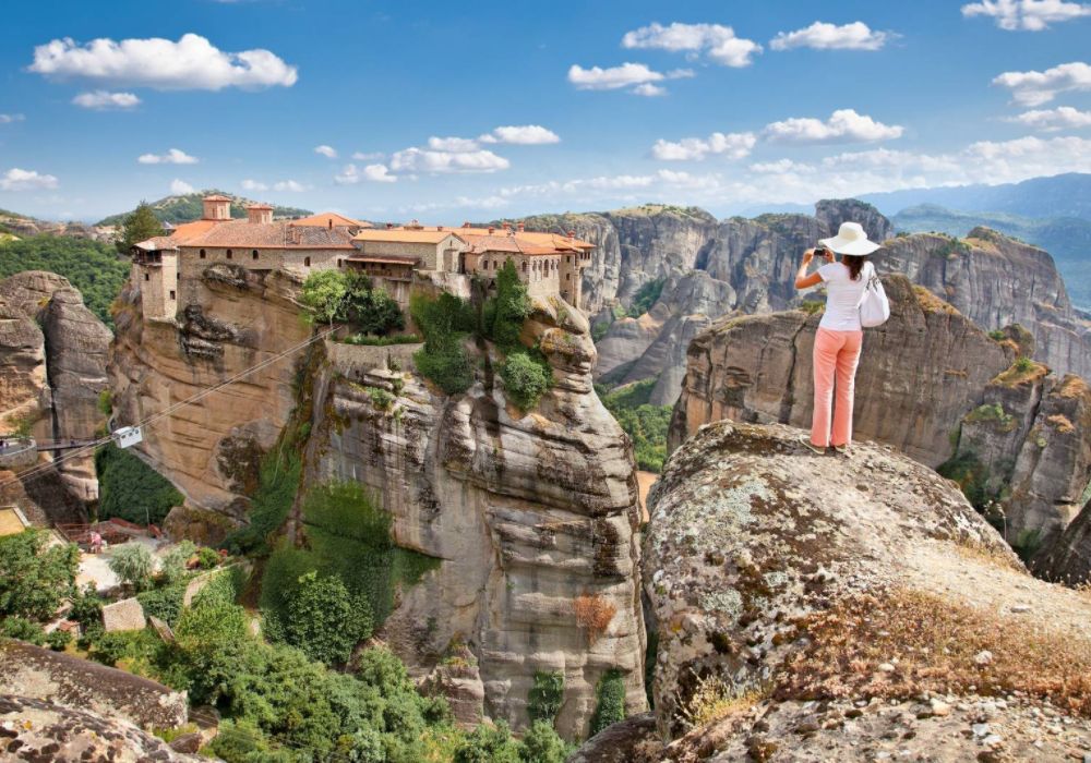 A woman taking photos on meteora rocks.