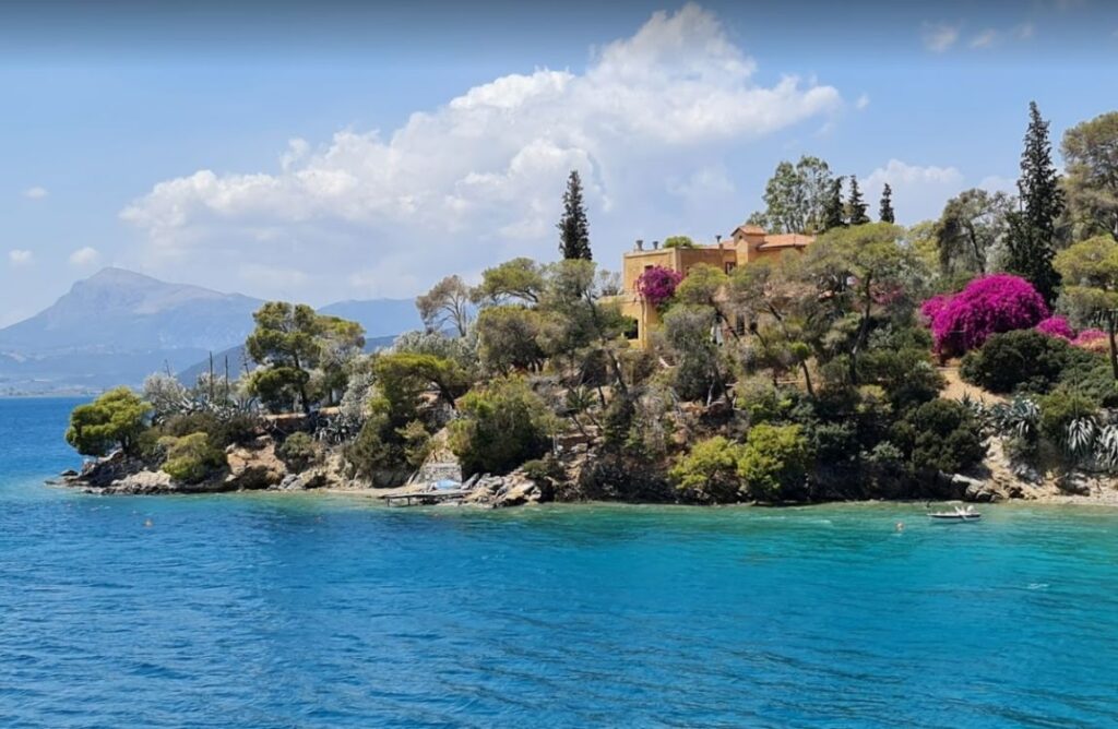 A beach called Limanaki tis Agapis with a house and lot of trees in a sunny day in Poros Island Greece.