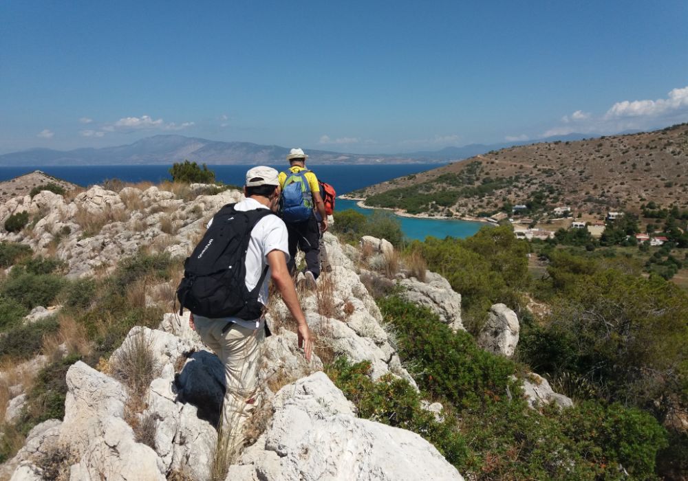 group of hikers on steel cliff walking towards the sea