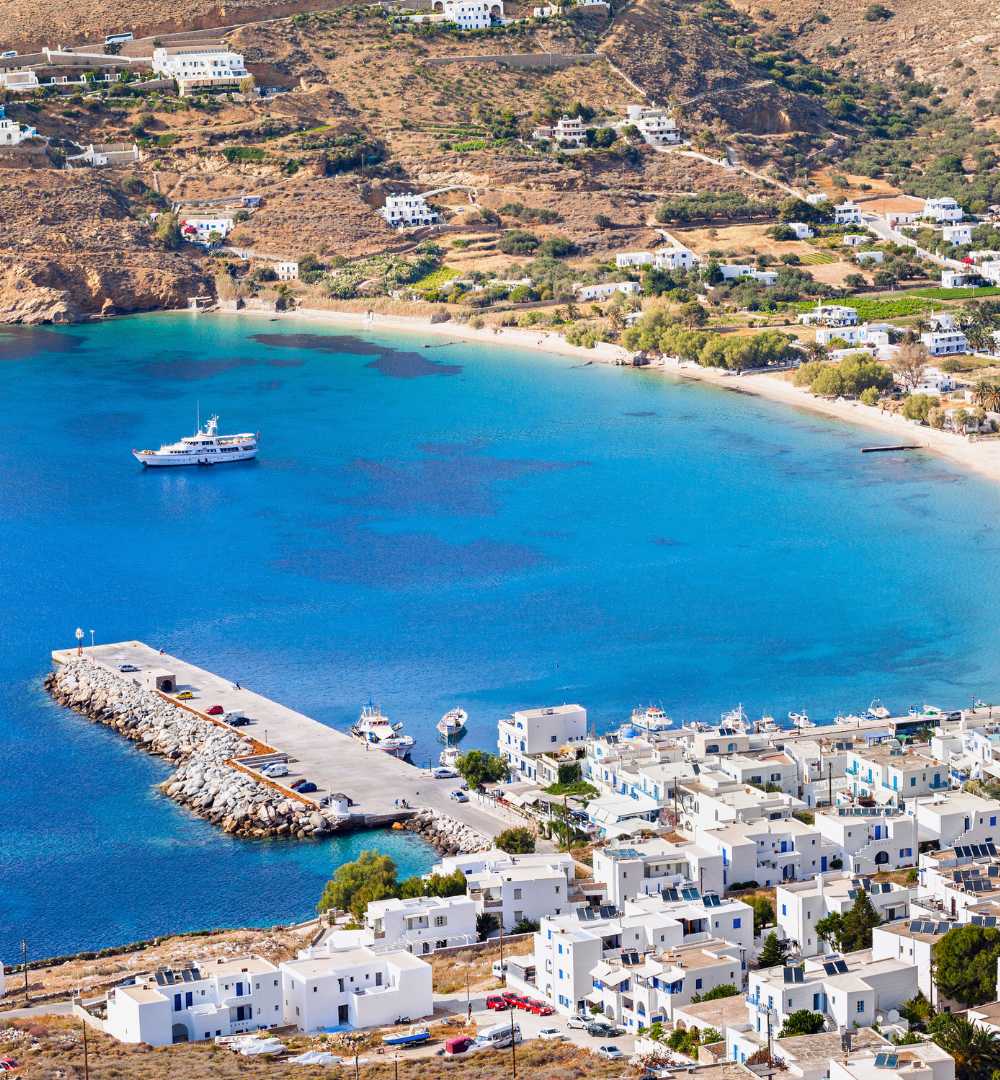 Aerial view of Aegiali Bay with turquoise waters, fishing boats, and white houses—perfect for an Amorgos travel guide and highlighting the best beaches in Amorgos.
