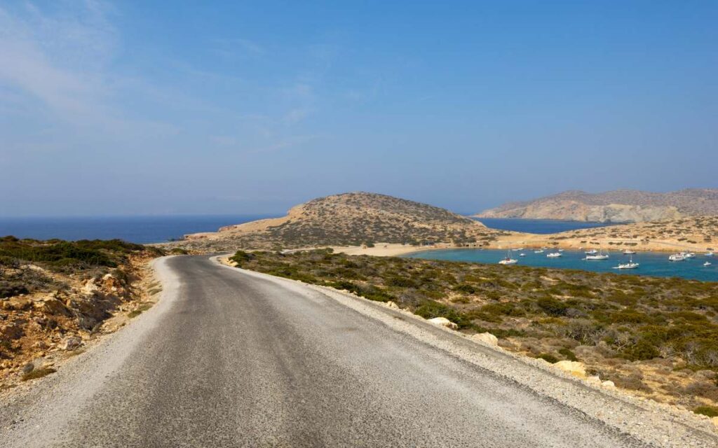 Scenic road leading toward Kalotaritissa Bay with blue sea views, showcasing the rugged landscapes of Amorgos Greece and top things to do.