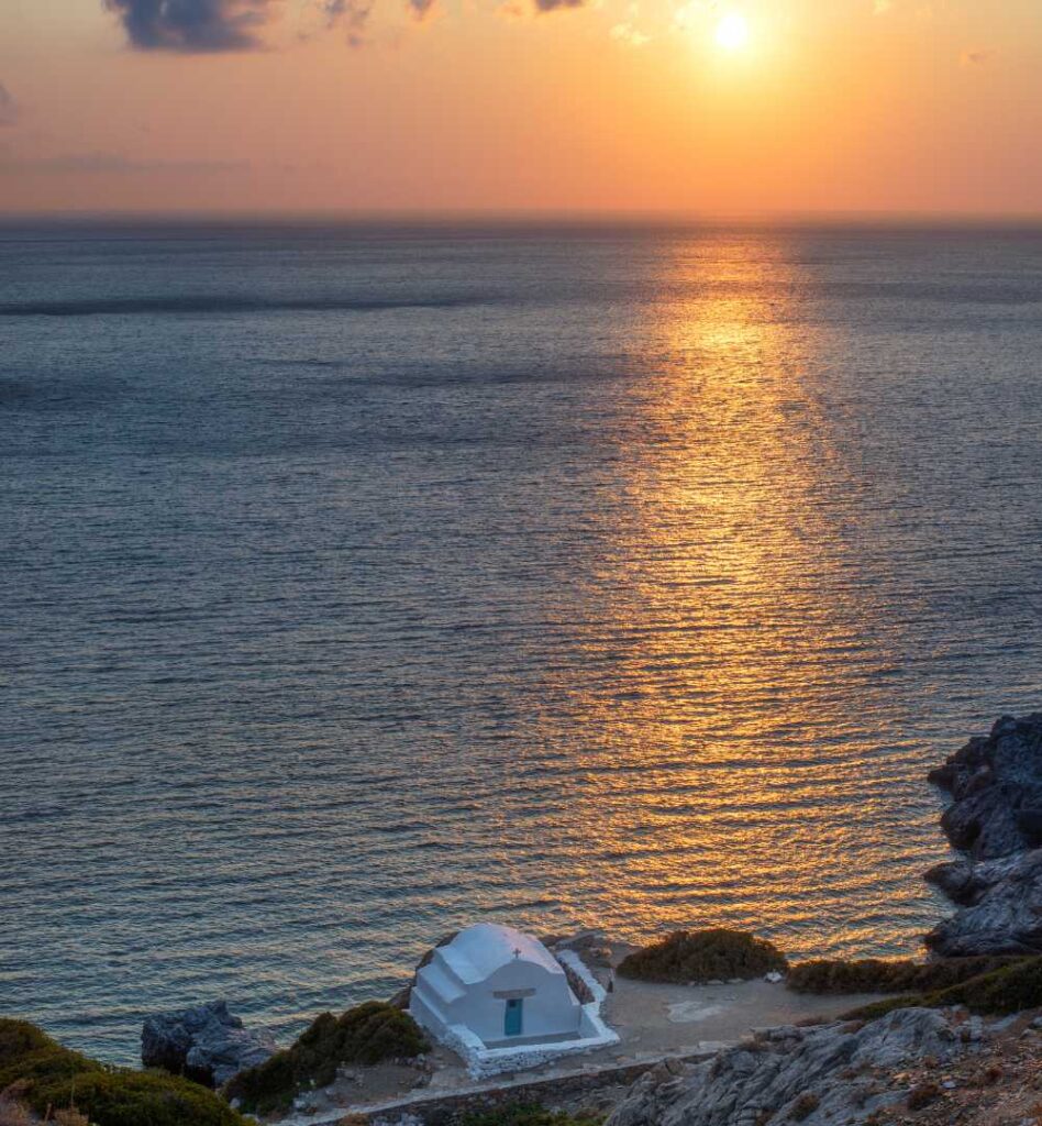 Sunset over the Aegean with a tiny white chapel on the cliffs of Amorgos Greece, a peaceful highlight for any Amorgos travel guide and things to do in Amorgos.