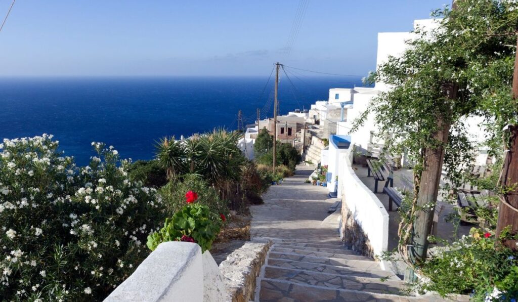 An alley with steps in Kasteli village with flowers houses and sea view