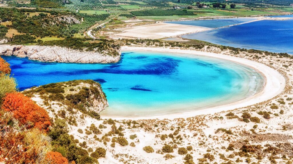 A beach called Voiokoilia with beautiful blue water in a sunny day. Voidokoilia is uniquely shaped like the Greek letter omega with a fine sandy beach.