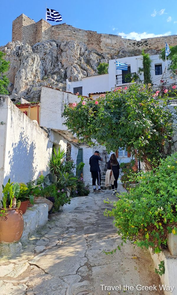 An alley of Athens Old Town Plaka with two people walking and view to Acropolis Hill.Greece in May.