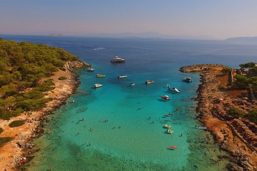 Aponisos beach with yachts and swimmers in Agistri island