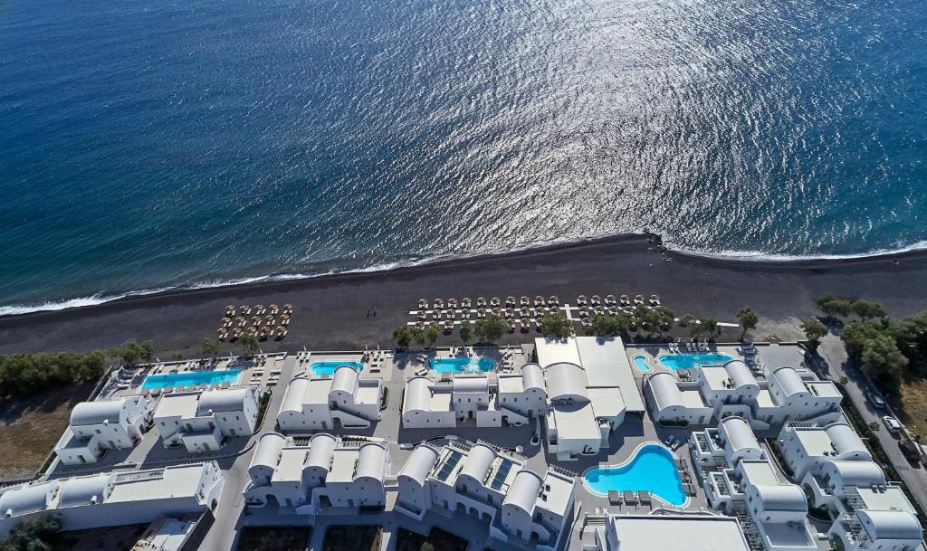 Santorini hotel buildings and pool by the sea from a drone