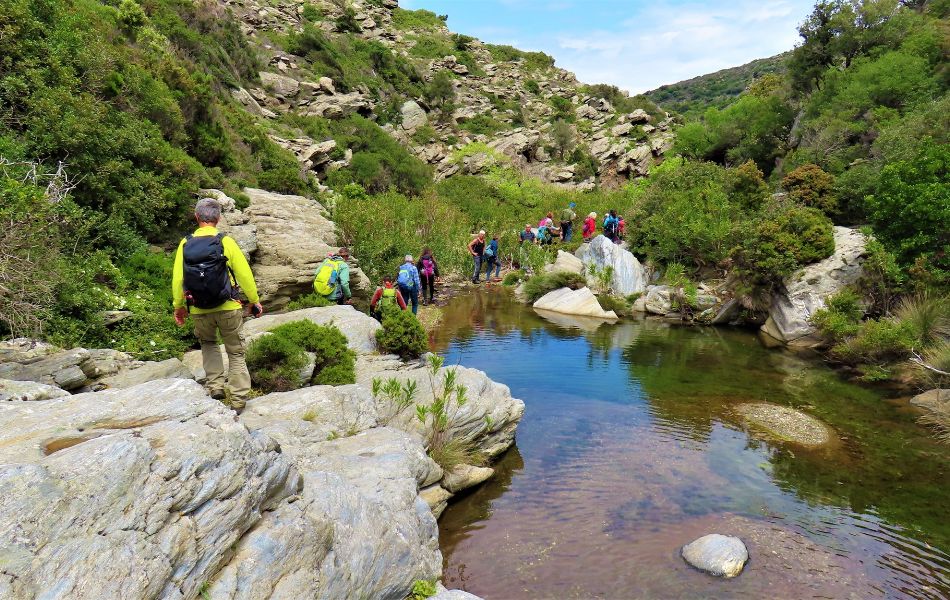 Hikers on Andros island crossing a small river. 