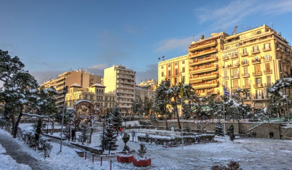 Thessaloniki town full of snow with buildings and some trees 