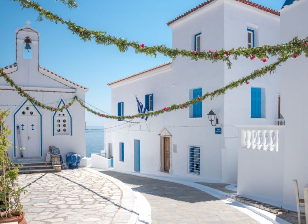 Whitewashed house and church adorned with flowers in Greece.