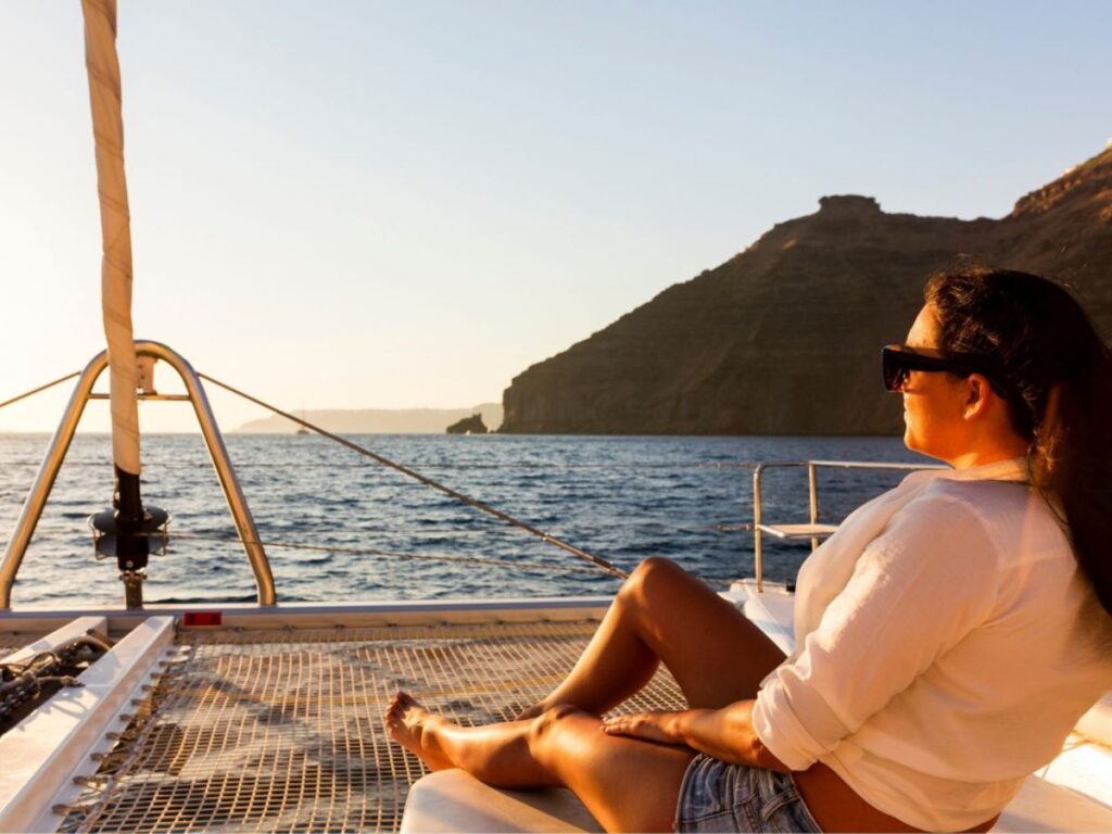 A woman on a yacht looking over at the sea in Santorini -  Things to do in Santorini