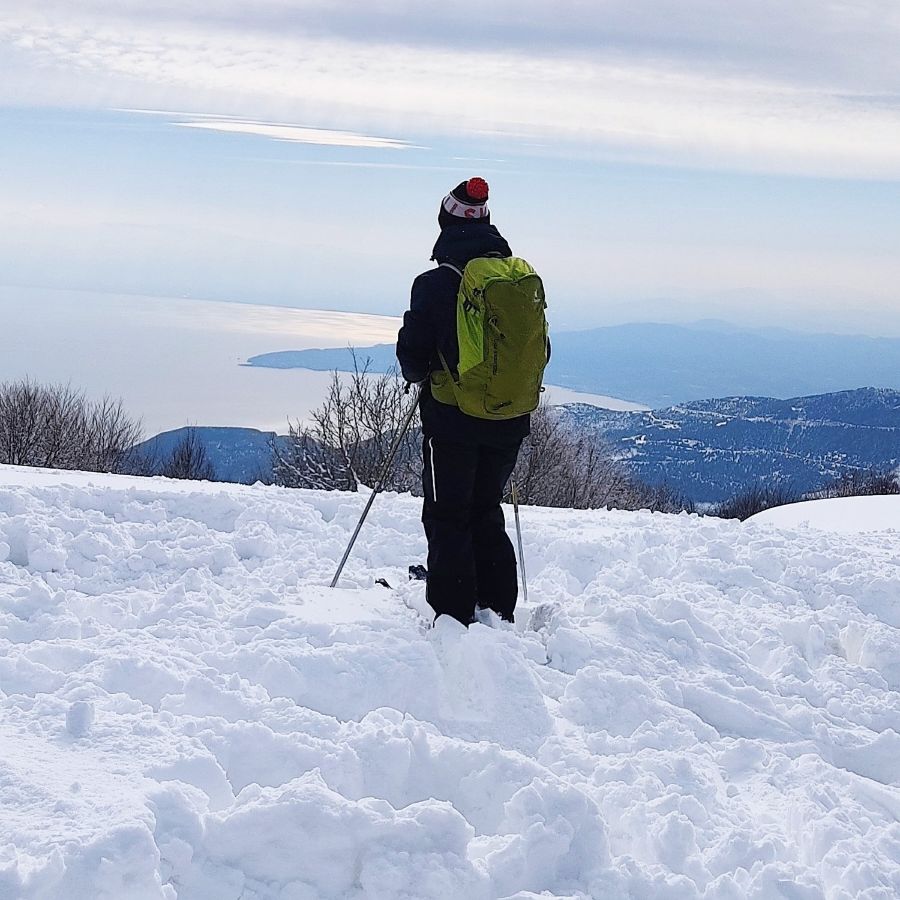 A woman dressed in ski aparel looking atthe sea in Pelion One of the best ski resorts in Greece.