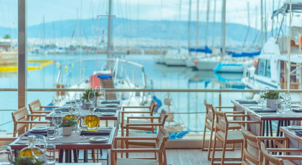 Athens Riviera. The seafront restaurant Varoulko, tables of the diner with sailing boats inside the sea in the background