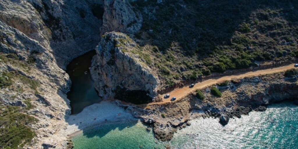A View Taken from a Drone with some cars on the road near by the sea in Kakia Lagkada Lake and Gorge in Kythira Island Greece.