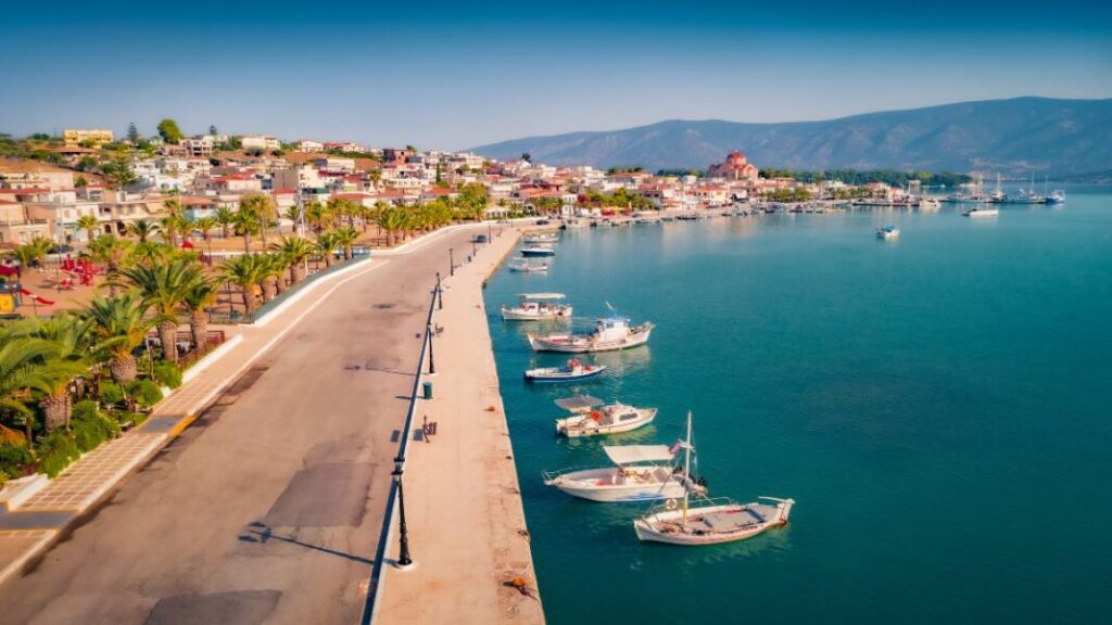 A port with small boats, trees and houses beside the sea in a sunny day in Porto Heli Peloponnese Greece.