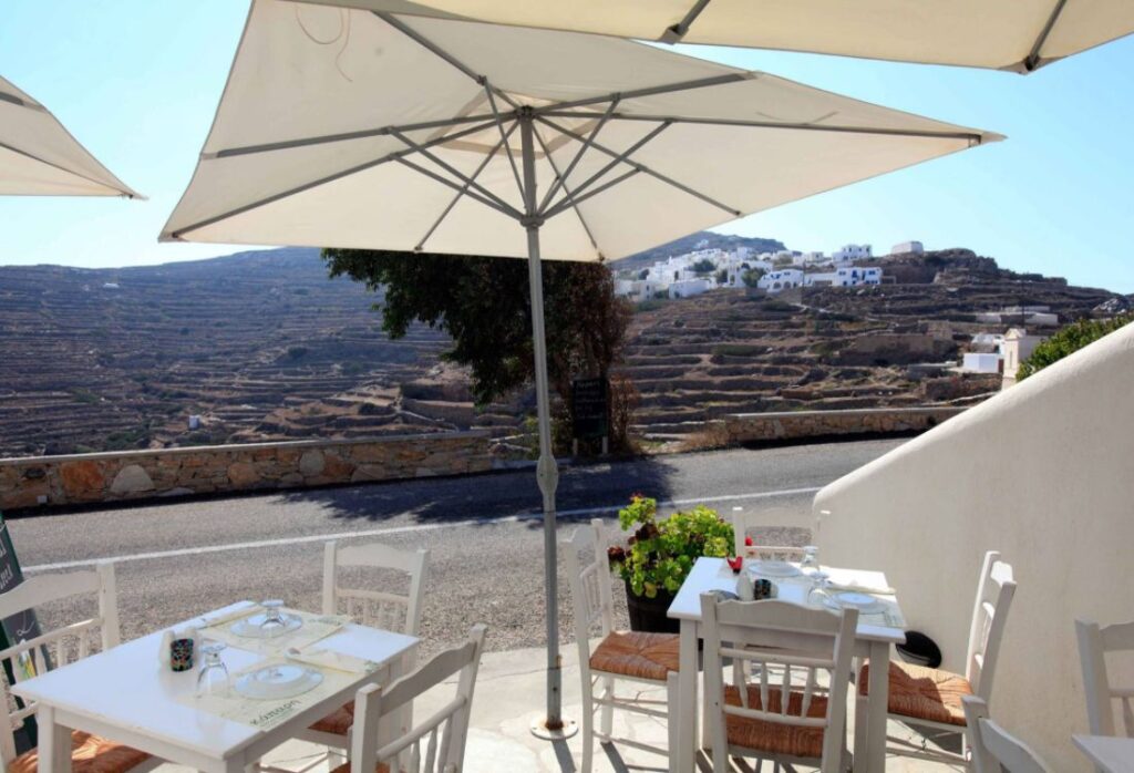 Kapari tavern with tables and chairs with view to whitewashed houses in Sikinos Island.