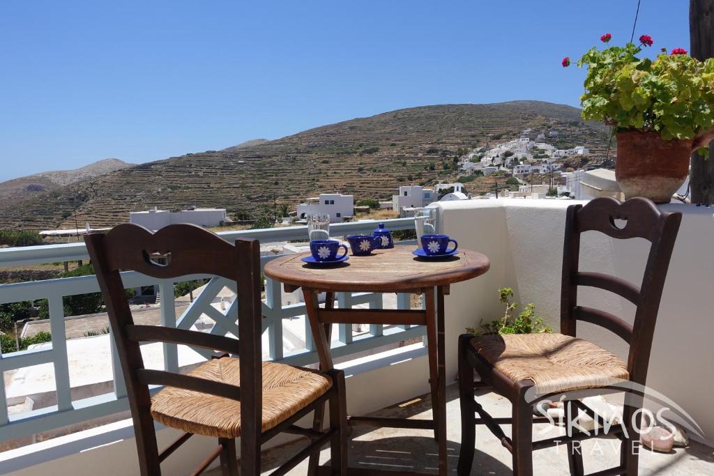 Traditional Apartment in Kastro with a table and two chairs on the balcony with view to whitewashed houses. Sikinos Greece.