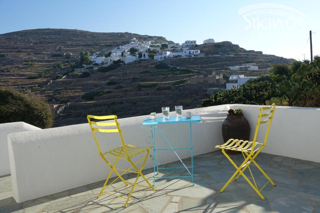 Sikinos Elegant Studio terrace with a view from the balcony with a table and two chairs to whitewashed houses. Sikinos Greece.