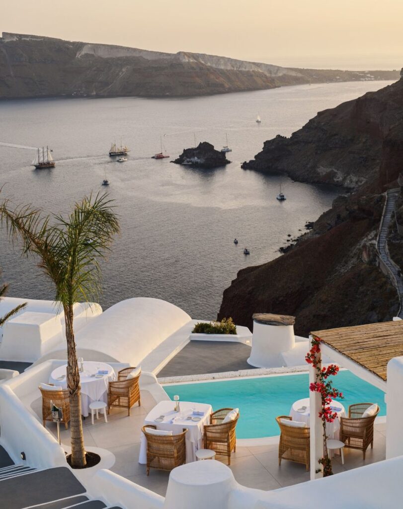 A stunning dining setup overlooking the caldera, featuring a pool and breathtaking sunset views.