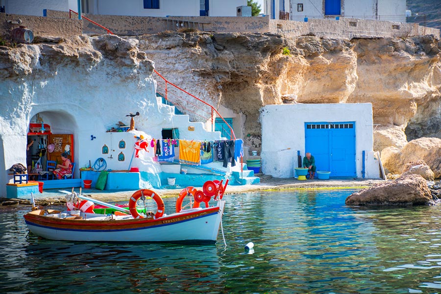 A Small Port and some people selling some things and a Fish Boat  in Milos Island.