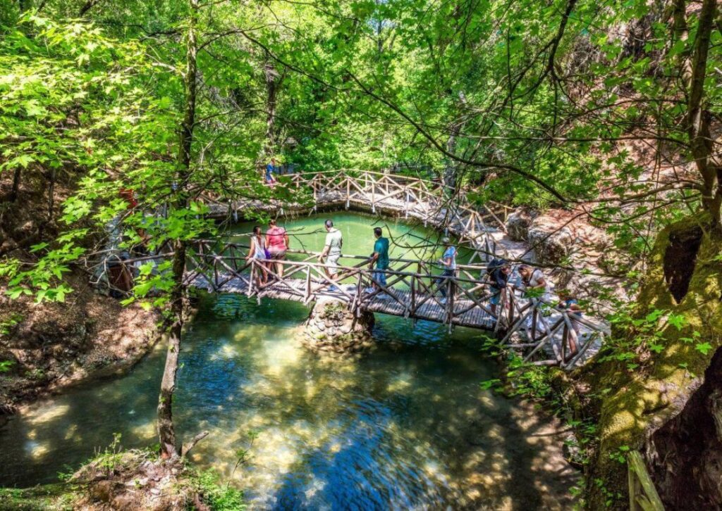 The Valley of the Butterflies and some people walking on a wooden bridge on Rhodes Island. 