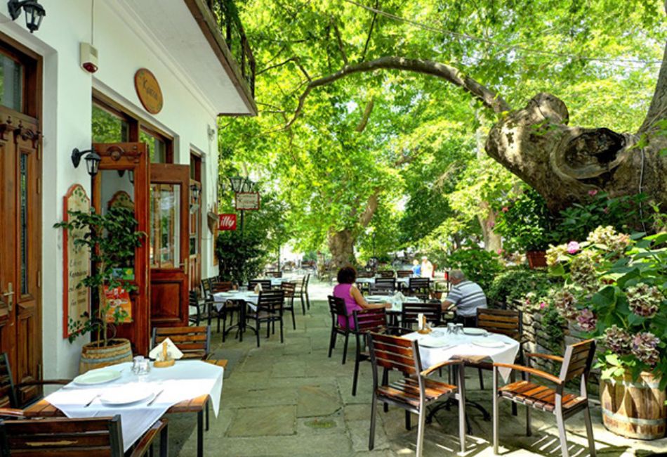 Kritsa tavern on the main square with tables and chairs outside and too people sitting. The Best Things to do in Portaria.