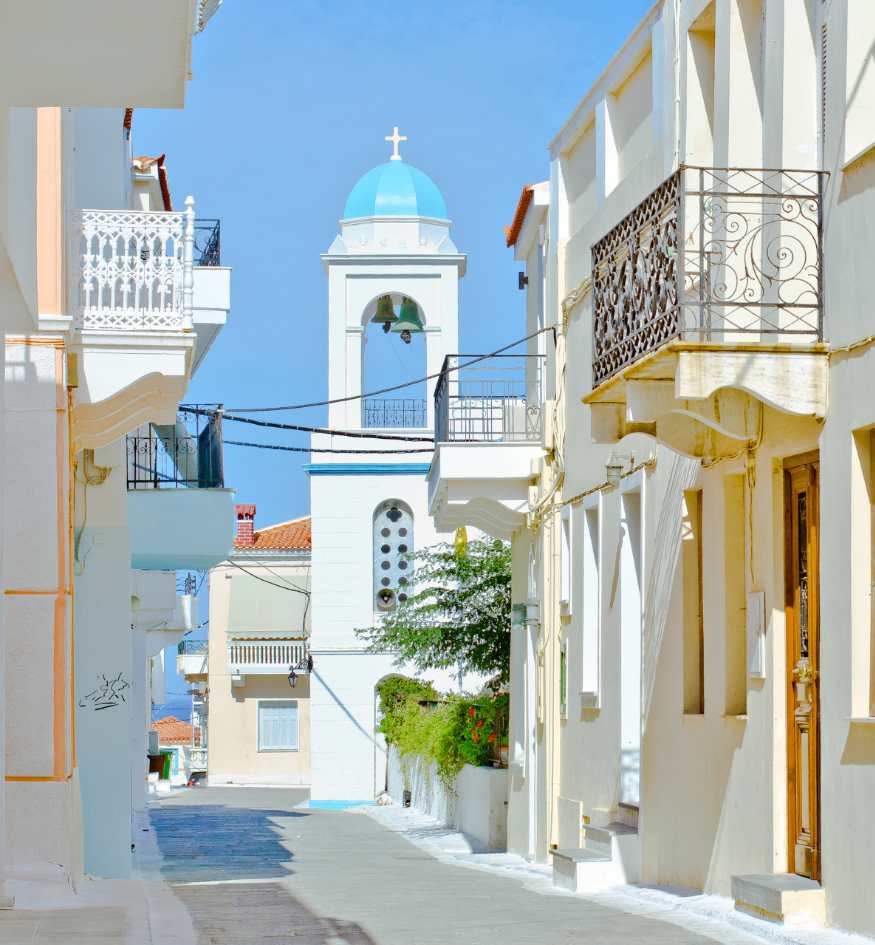 A classic blue-domed white church overlooking the Aegean Sea on Andros island, Greece in April.