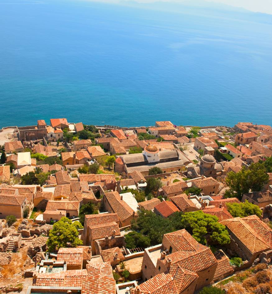 Bright spring flowers bloom along the stone walls of the medieval castle town of Monemvasia overlooking the Aegean Sea.
