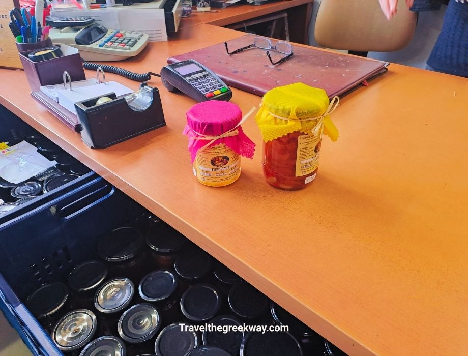 Two jars of traditional Pelion jams in bright fabric covers on a shop counter in Portaria.