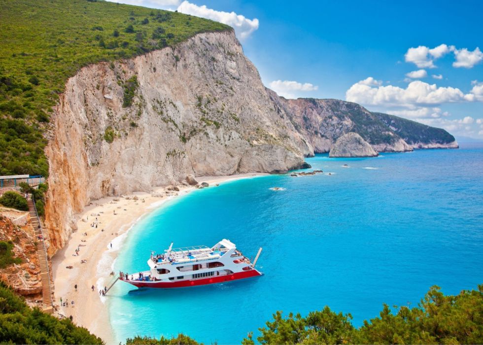 Katsiki Beach in Lefkada with many people on the beach and a yacht in the sea. Best Places to Go to Greece in April.