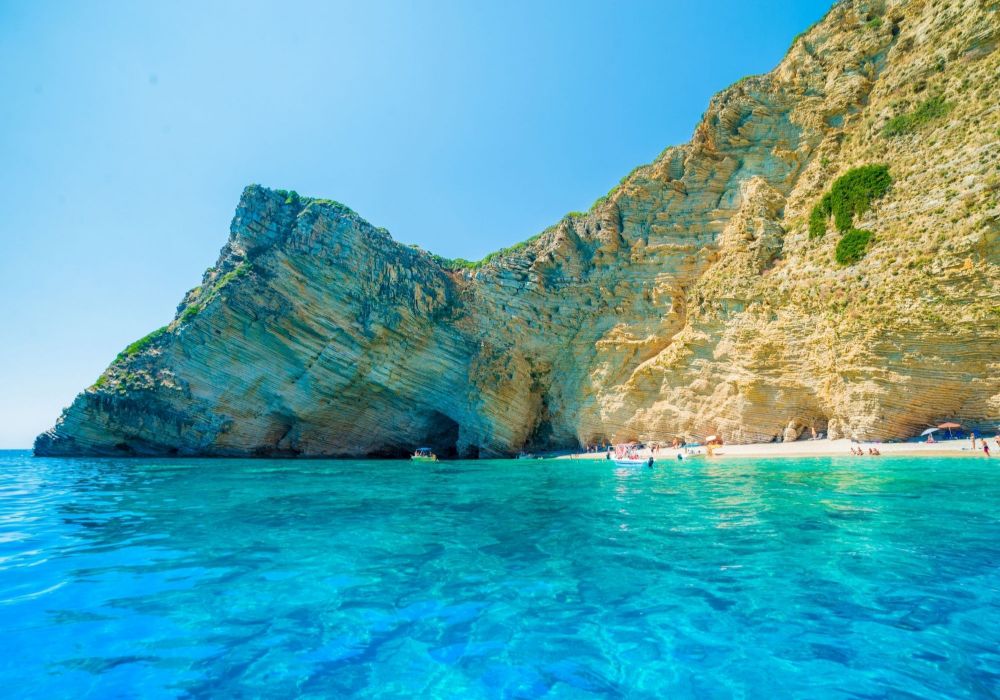 A sandy beach with some people swimming.