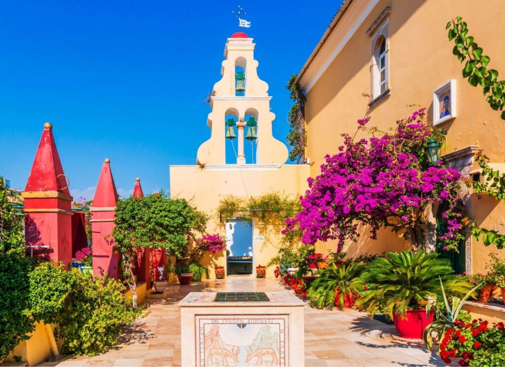 Theotokos Monastery in Paleokastritsa with plants in pots and voukamvilia in a sunny day.