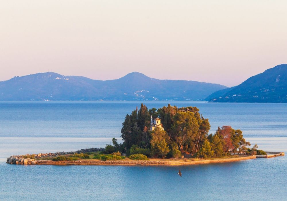  View to Pontikonisi from Corfu with lot of trees and a small Greek Church. 