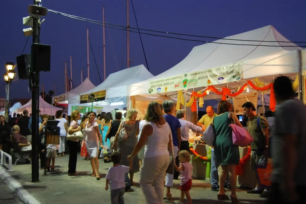 Aegina Pistachio festival with many kiosks and people walking around them. 