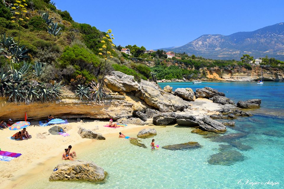 Scenic Pessada beach with crystal-clear waters, rocks, and sunbathers in a natural setting.
