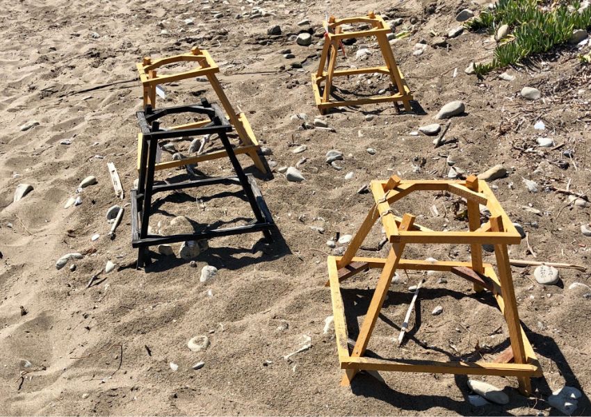 Wooden frames on a sandy beach used for protecting sea turtle nests.