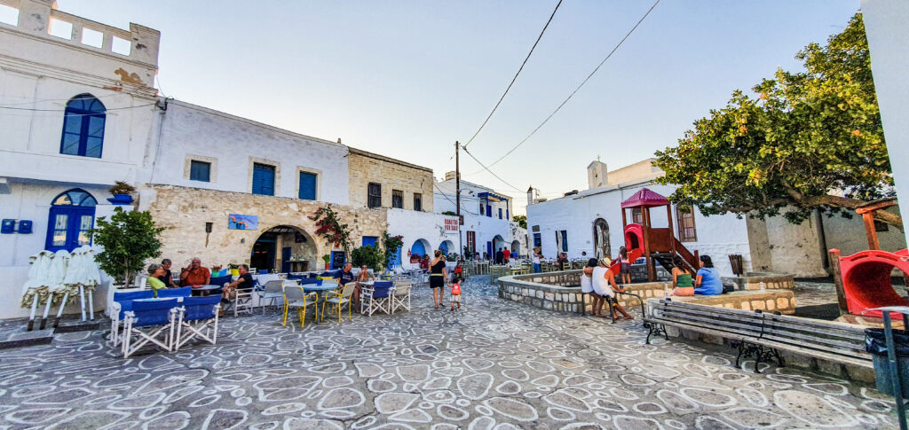  Chorio square in Kimolos with people sitting in chairs and tables. 